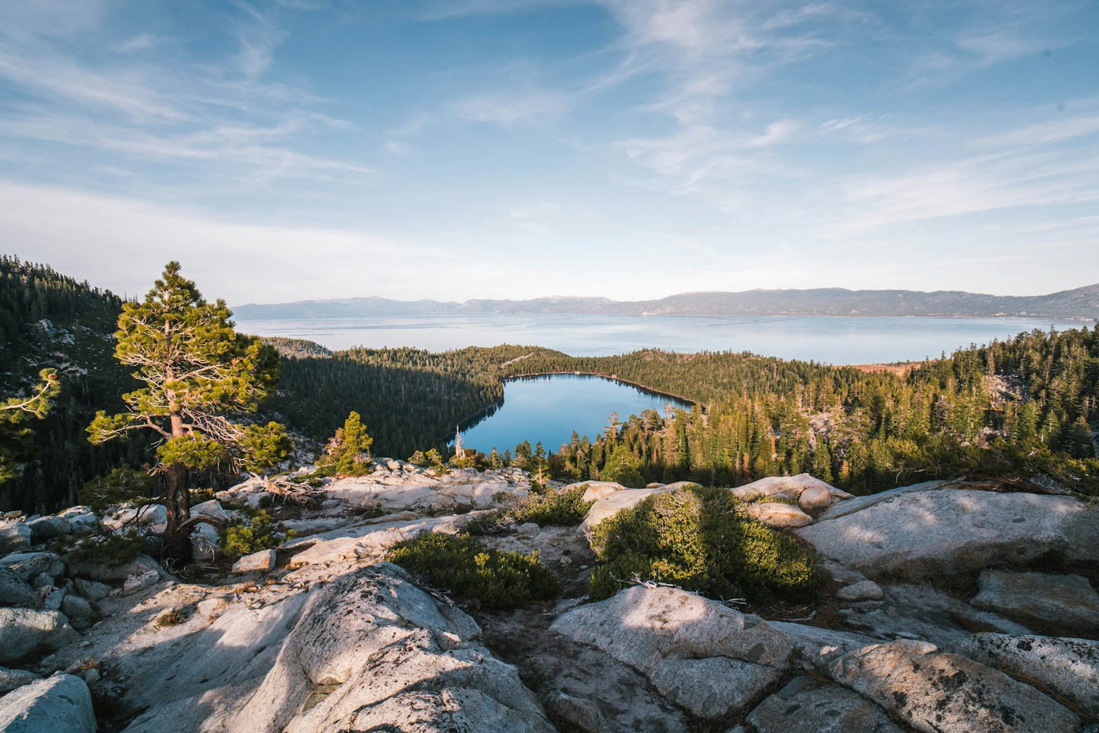 rock formations viewing lake surrounded with green trees under white and blue sky